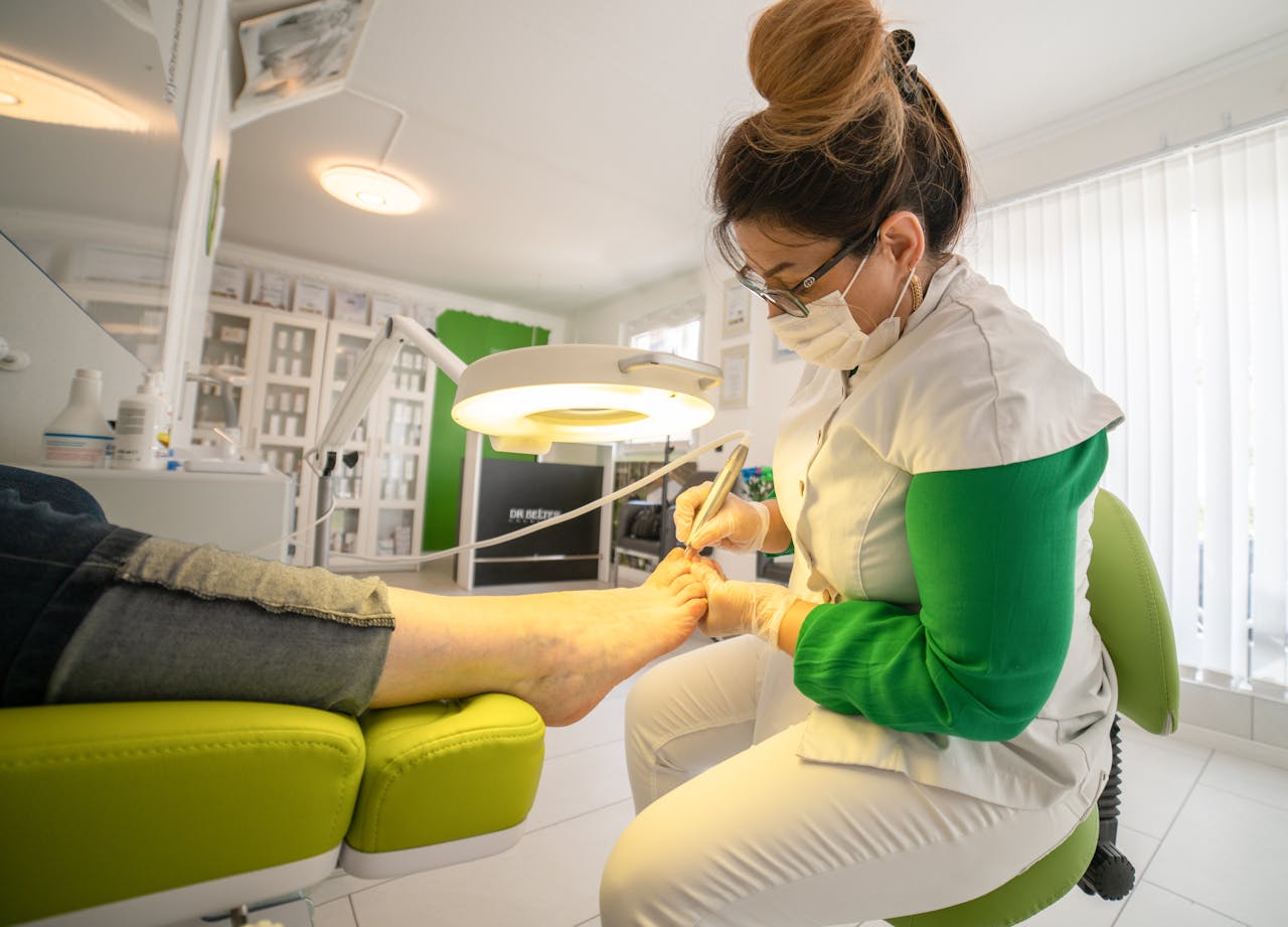 service-01 Side view of serious female in medical uniform and mask making hardware pedicure using modern equipment